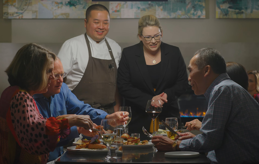 Diners enjoying meal with attentive restaurant staff.