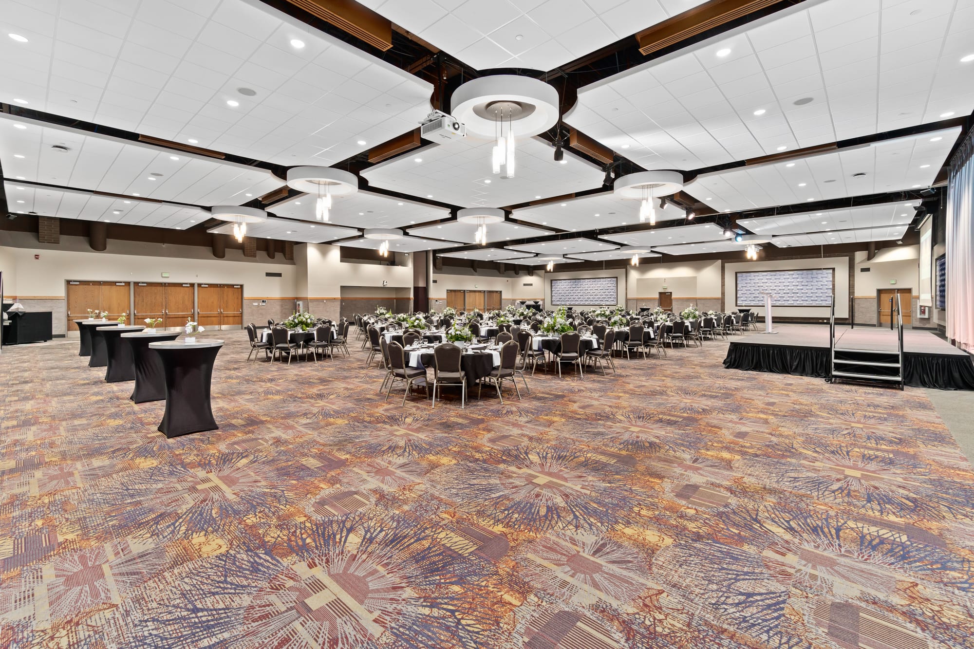 Elegant banquet hall with decorated tables and stage.