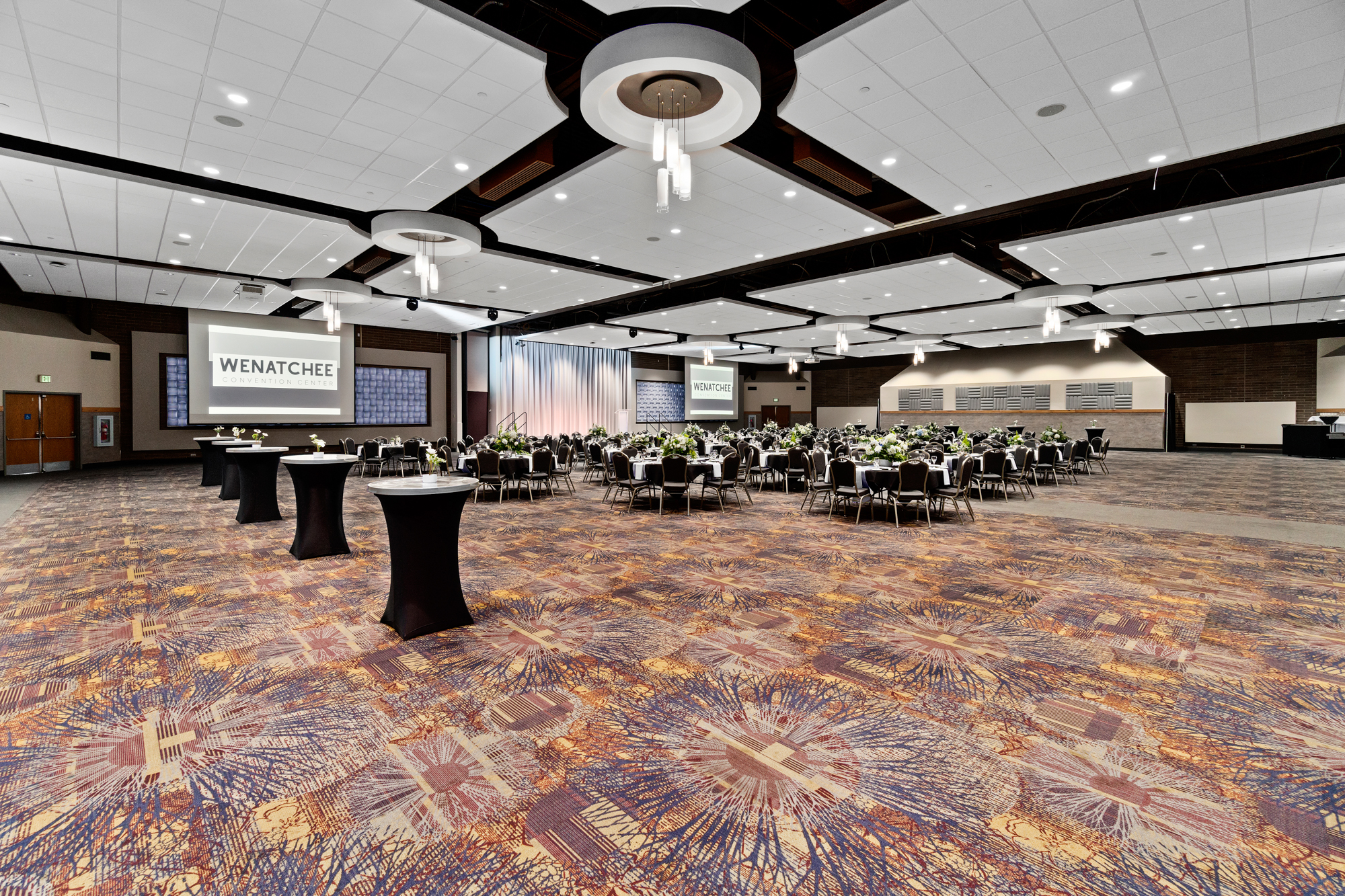 Spacious banquet hall, tables set for event.