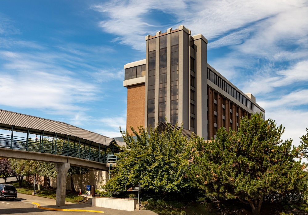 Modern building with sky bridge and trees.