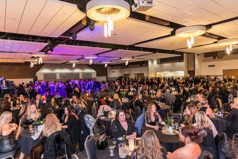 Large indoor event with people seated at tables.