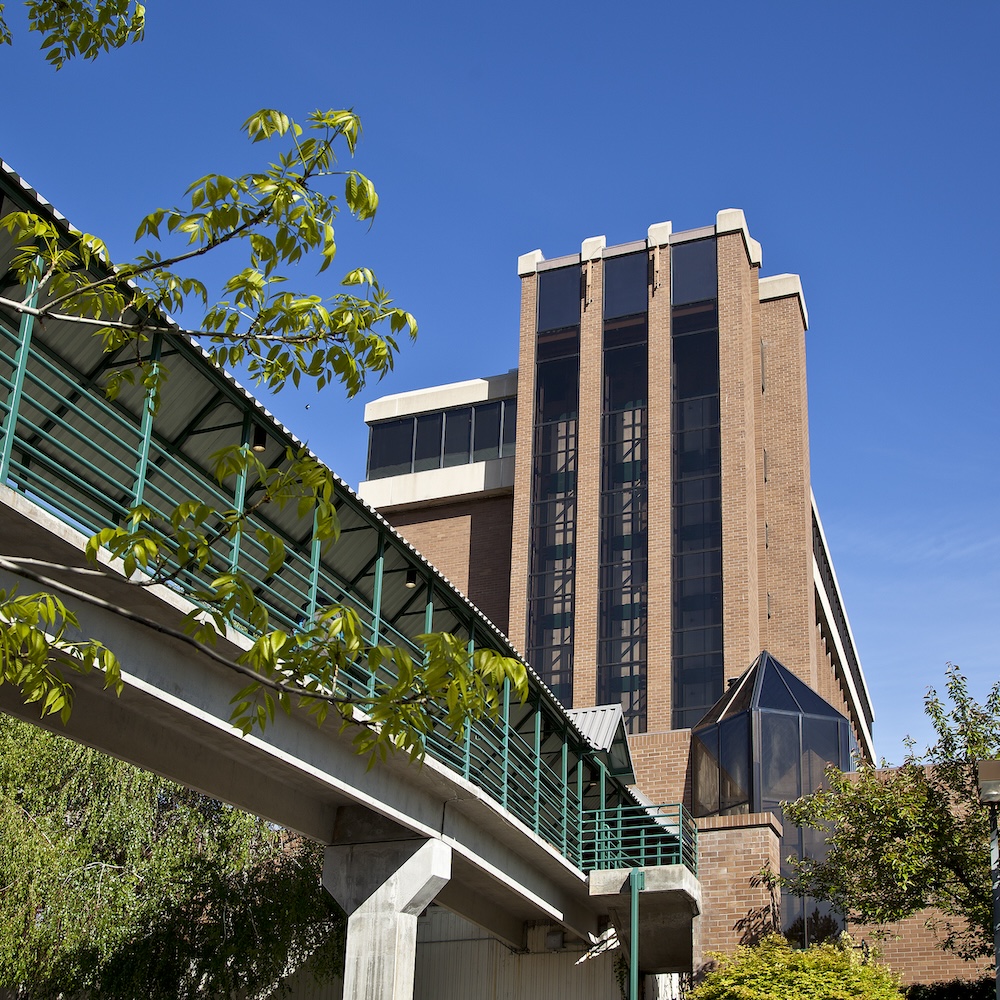 Modern brick building with elevated walkway and trees.