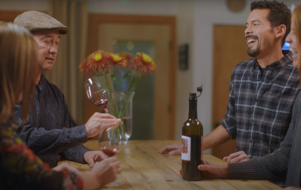 People enjoying wine tasting at a wooden table.