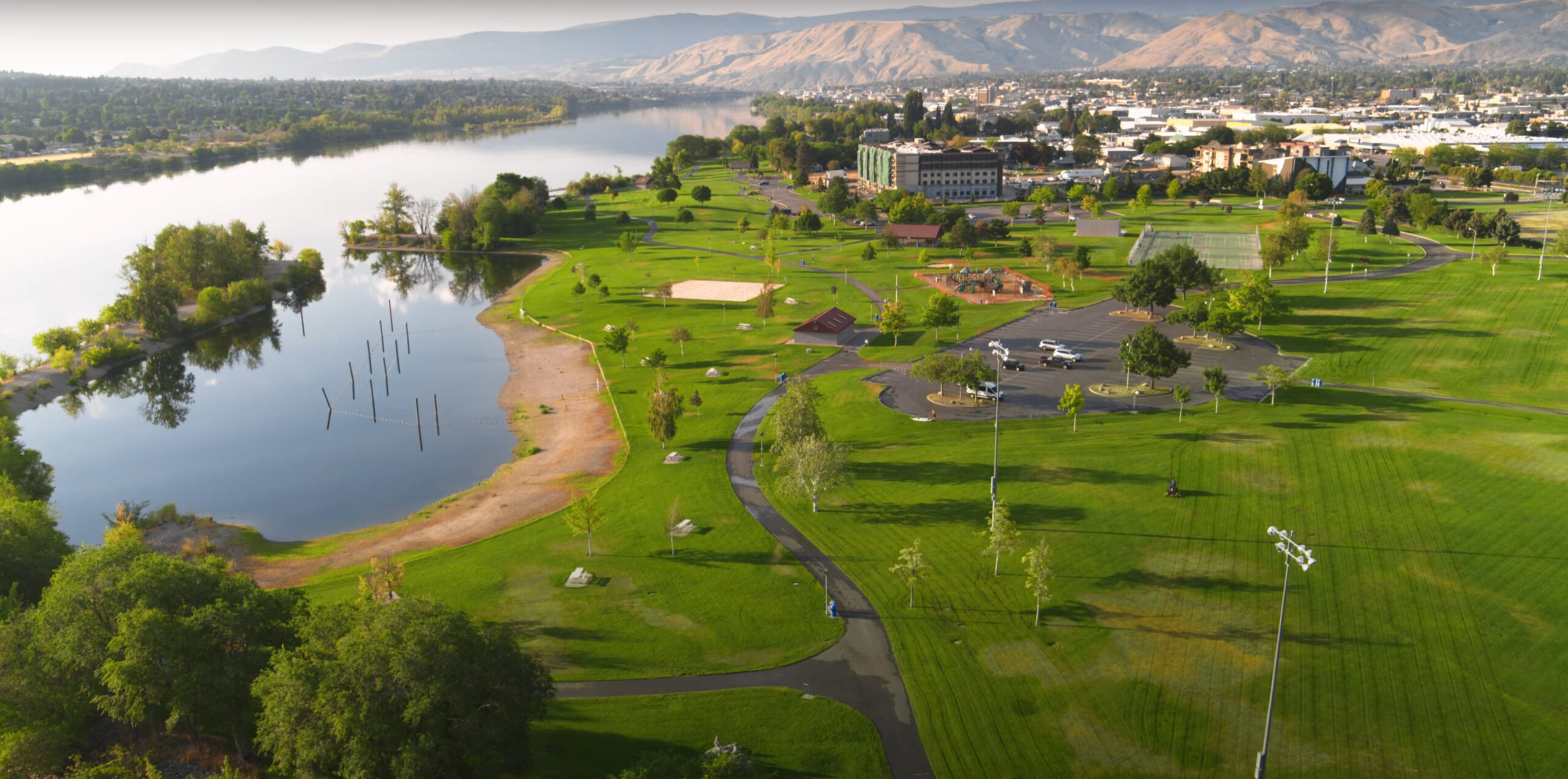 Aerial view of park by river and cityscape