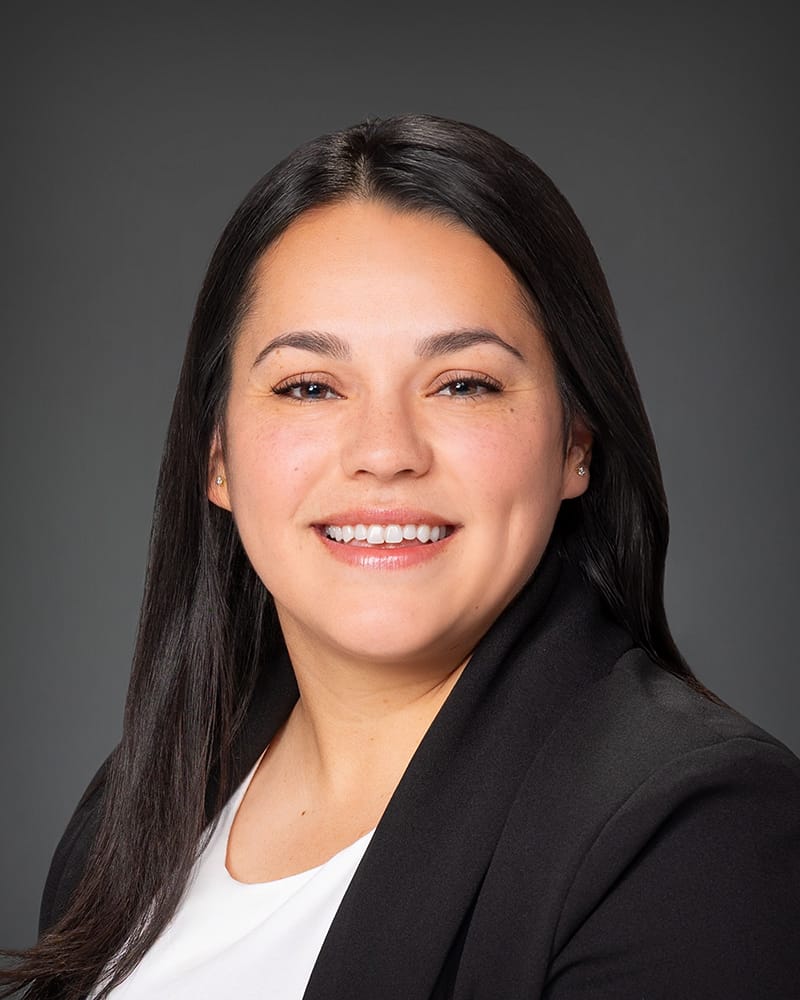 Professional woman smiling, wearing blazer, portrait photo.
