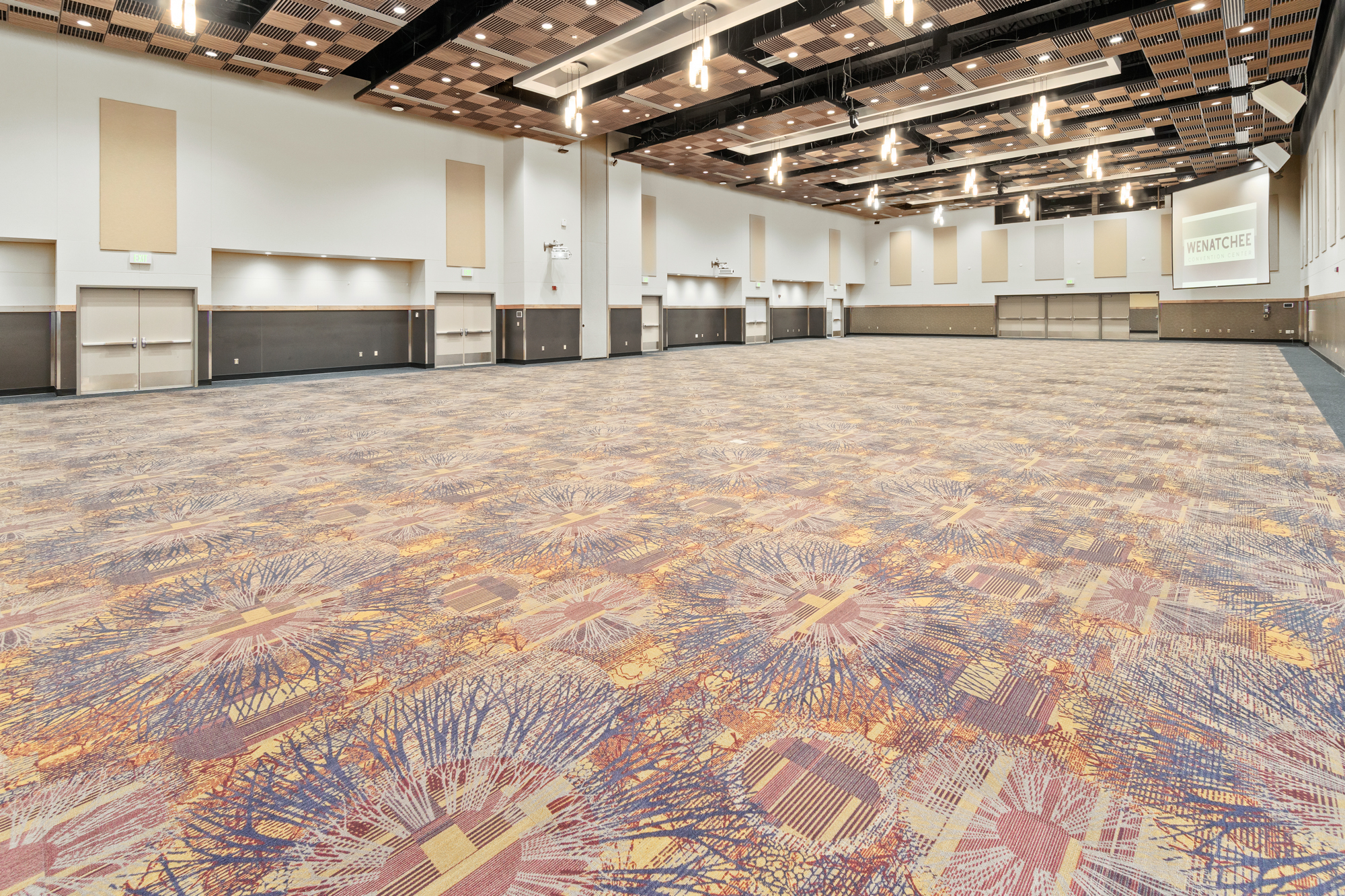 Spacious conference room with patterned carpet and stage.
