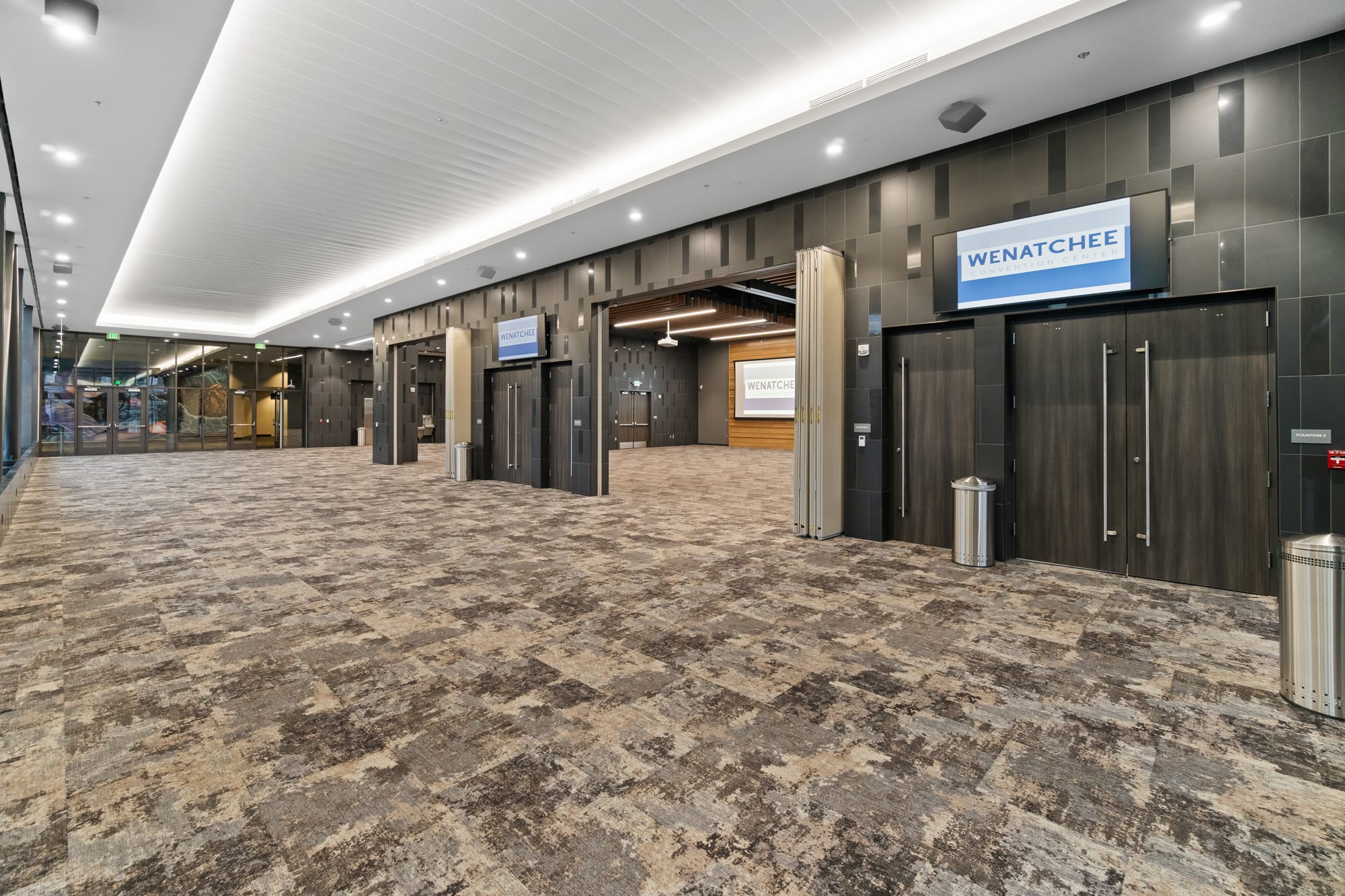 Spacious convention center hallway with signs and doors.