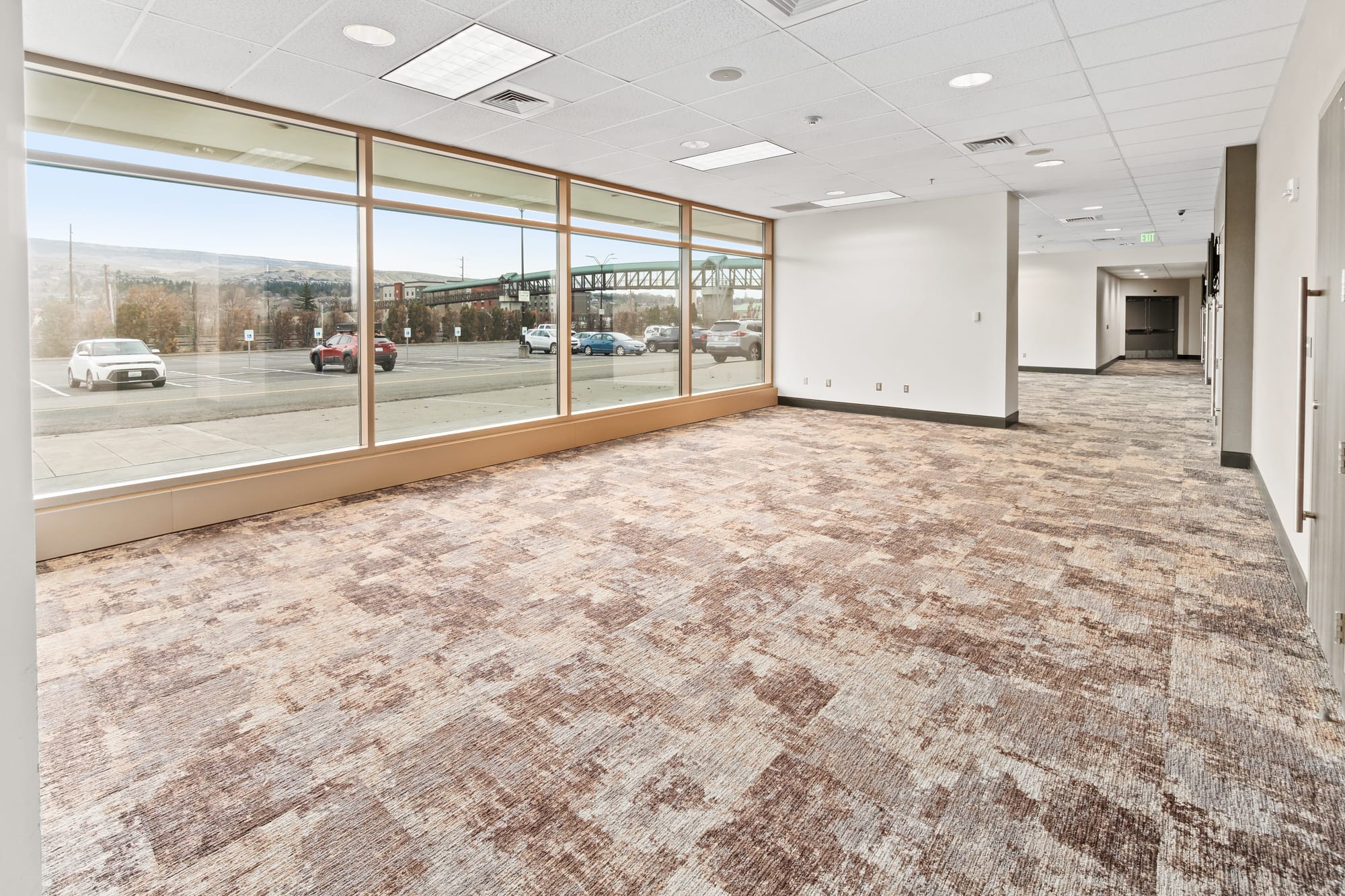 Empty office space with large windows and carpet.