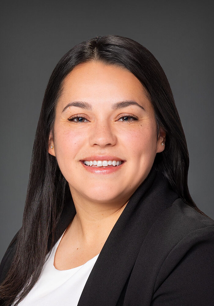 Professional woman smiling, wearing blazer, portrait photo.