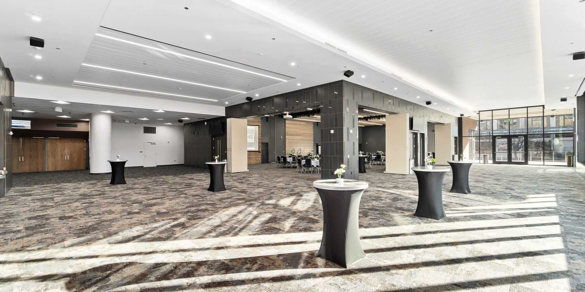 Spacious modern event hall with few tables and chairs.